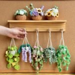 Crocheted hanging plant pots with colorful flowers on a wooden shelf