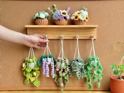 Crocheted hanging plant pots with colorful flowers on a wooden shelf