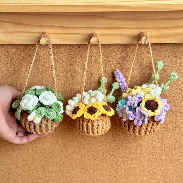 Three crocheted hanging flower pots with different arrangements