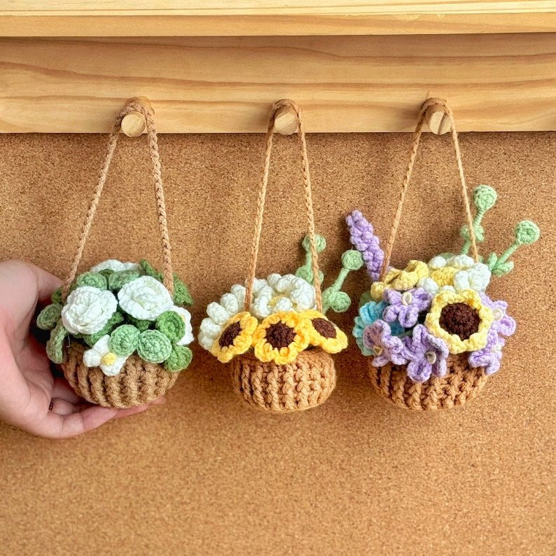 Three crocheted hanging flower pots with different arrangements